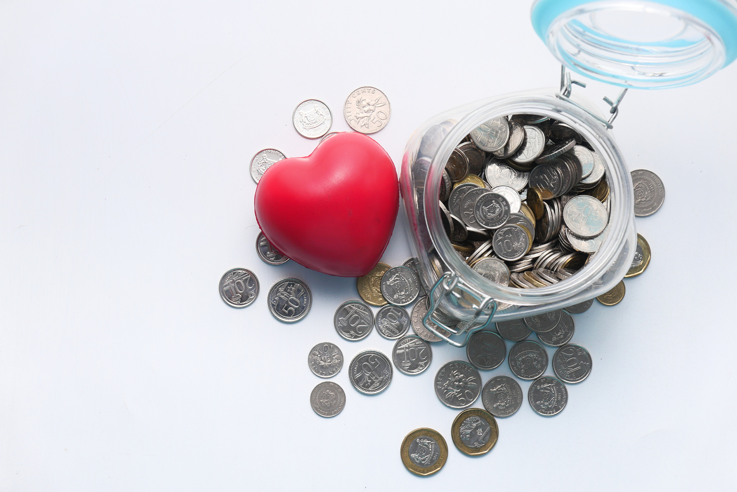 Red Heart and Coins in a Jar on White Background